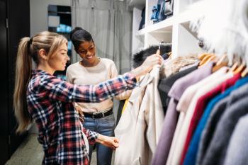 Two girlfriends choosing clothes, shopping. Shopaholics in clothing store, consumerism lifestyle, fashion