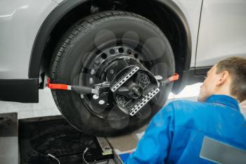 Mechanic adjusts the target on collapse of convergence stand in auto-service. Computer diagnostic of car suspension