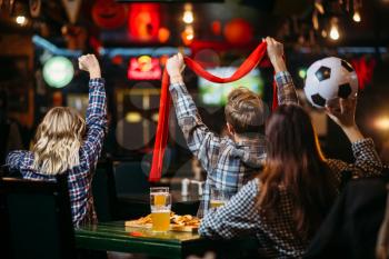 Group of football fans with scarf and ball watching match and drinks beer in sports bar. Tv broadcasting, young friends leisures in pub, favorite team wins