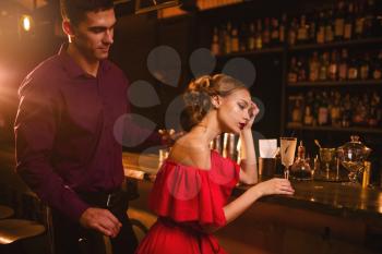 Date in nightclub, attractive couple against bar counter. Woman in red dress and her man, love relationship, night lifestyle