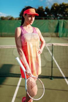 Athletic woman with tennis racket poses on outdoor court. Summer season active sport game