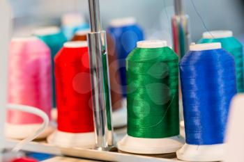 Spools of color threads closeup, sewing material. Cloth factory, weaving, textile production, clothing industry