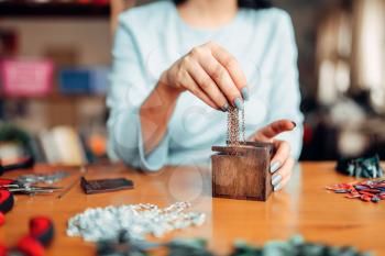 Female person hands pulls out a metal chain from a wooden box, master at work. Handmade jewelry. Needlework, bijouterie making