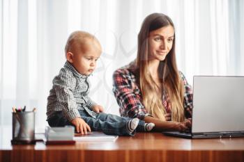 Mother and little kid looks on laptop screen. Mom and son happy together at home