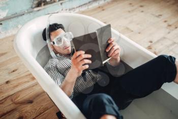 Funny businessman in flippers and mask lies in bathtub and reads a book, humor. Business lottery concept