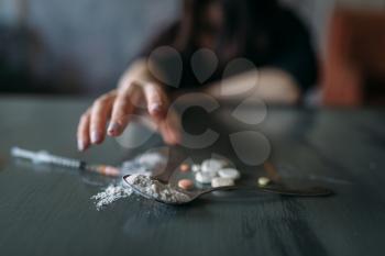 Female junkie hand hand reaching for the dose on the table. Drug addiction concept