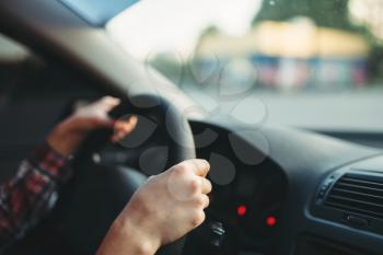 Female car driver beginner clung to the wheel, driving school concept. Automobile exam or test on the street