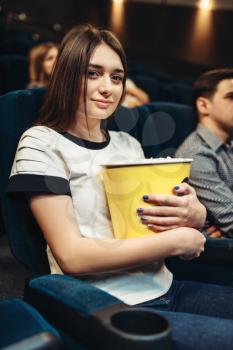 Young woman eats popcorn while watching movie in cinema. Showtime