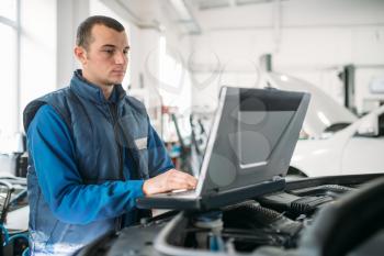 Engineer makes computer diagnostics of the car in auto service. Vehicle wiring inspection
