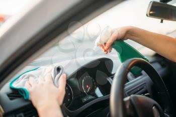 Female person polishes the dashboard of the car, polishing process on carwash. Lady on self-service automobile wash. Outdoor vehicle cleaning at summer day