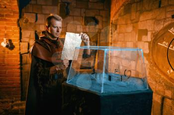 Traveler solving ancient map in the temple dungeon. Old secrets, fantasy labyrinth. Man at the glass cave model