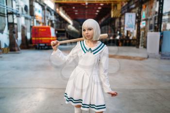 Cute anime style blonde girl with baseball bat. Cosplay fashion, asian culture, doll in dress, sexy woman with makeup in the factory shop