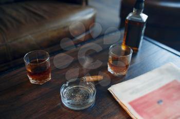 Whiskey and cigar on wooden table in retro office, nobody. Alcohol beverage, tobacco and newspaper, luxury vinage style