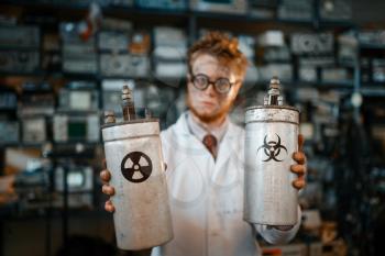 Strange scientist holds radiation materials in his hands, dangerous test in laboratory. Electrical testing tools on background. Lab equipment, engineering workshop