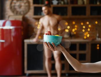 Nude young husband poses on the kitchen. Naked man and woman preparing breakfast at home, food preparation without clothes, love couple cooking in underwear