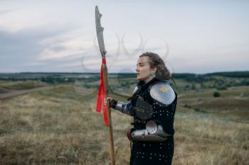 Female medieval knight with spear poses in armor, great tournament. Armored ancient warriors in armour posing in the field