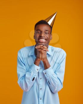 Cheerful man in cap, yellow background. Smiling male person got a surprise, event or birthday celebration, waiting for a surprise