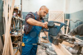 Carpenter in uniform works on circular saw, woodworking, lumber industry, carpentry. Wood processing on furniture factory, production of products of natural materials
