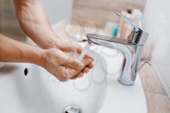 Man washes his face in bathroom, routine morning hygiene. Male person at the sink performs skin and body treatment procedures