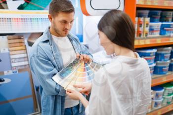 Young couple choosing color palette in hardware store. Male and female customers look at the goods in diy shop