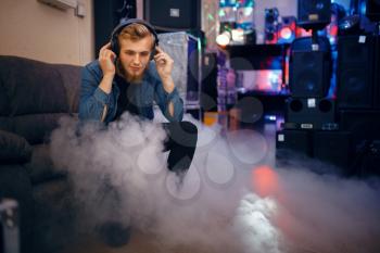 Bearded young musician choosing headphones in music store. Assortment in musical instrument shop, professional equipment for performers