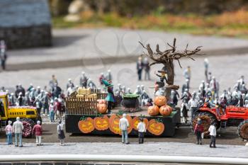 People celebrate halloween on city street, pumpkins and a witch in a cart, miniature scene outdoor, europe. Mini figures with high detaling of objects, realistically diorama, toy model