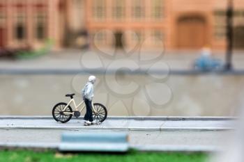 Man with bicycle on city street, miniature scene outdoor, europe. Mini figures with high detaling of objects, realistically diorama, toy model