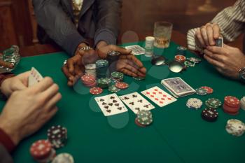 Poker players hands with cards, gaming table with green cloth on background, casino. Games of chance addiction, risk, gambling house. Men leisures with whiskey and cigars