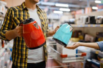 Young couple choosing electric kettle in electronics store. Man and woman buying home electrical appliances in market
