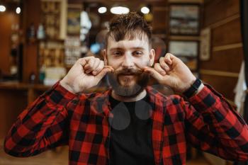Barber twists his mustache. Professional barbershop is a trendy occupation. Male hairdresser in retro style hairdressing salon