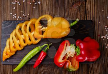 Fresh cutted pepper on board, top view, on wooden background. Organic vegetarian food, grocery assortment, natural products, healthy lifestyle concept