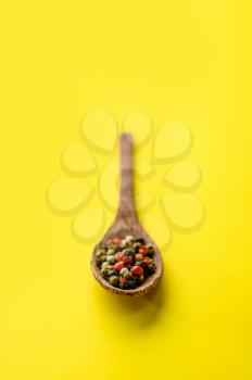 Fragrant spices in a spoon closeup, isolated on yellow background. Organic vegetarian food, grocery assortment, natural eco products, healthy lifestyle concept