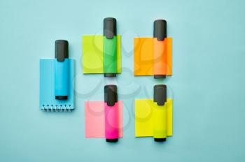 Colorful permanent markers and notepads on blue background. Office stationery supplies, school or education accessories, writing and drawing tools