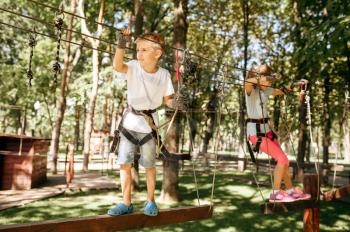 Little girl and boy climbs in rope park. Children climbing on suspension bridge, extreme sport adventure on vacations, danger entertainment outdoors
