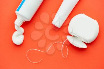 Oral care products, red background, nobody. Morning healthcare procedures concept, toothcare, toothpaste tube and dental floss