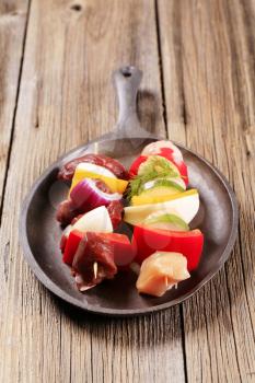 Raw Shish kebabs on a cast iron skillet