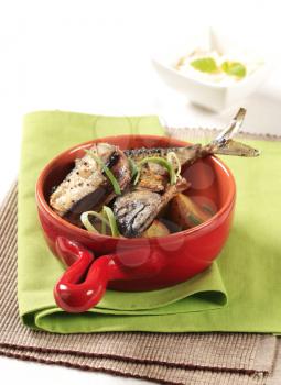 Spiced mackerel with roasted potatoes in a red pan