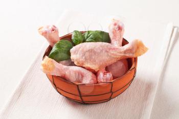 Raw chicken drumsticks in a terracotta bowl