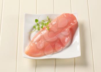 Raw chicken breast on a white plate