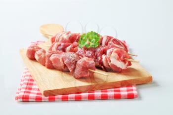 Raw pork skewers on cutting board