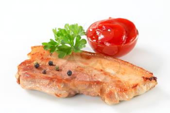 Slice of pan fried pork belly and tomato sauce