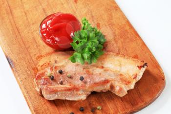 Slice of pan fried pork belly and tomato sauce