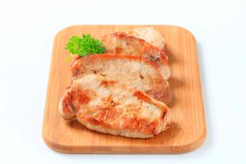 Pan seared pork cutlets on cutting board