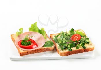 Slices of white bread with ham and salad greens