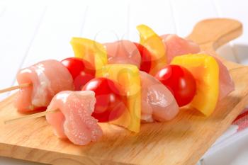 Pieces of raw chicken and vegetables on skewer