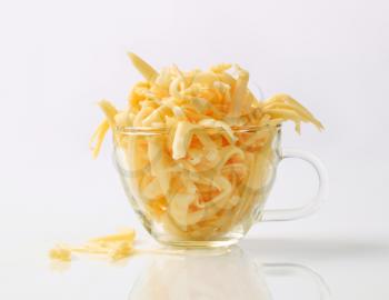 Grated yellow cheese in a glass cup 