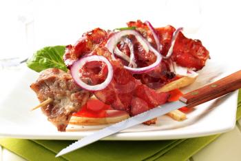 Grilled meat on skewer with crispy rashers of bacon and vegetables