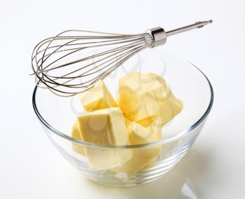 Blocks of fresh butter in a bowl and metal whisk