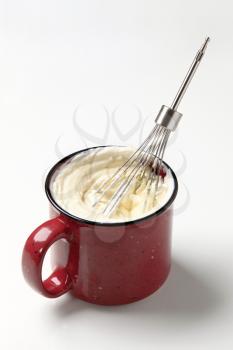 Whisking cream in an enamel mug - studio