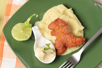 Fried breaded dinosaur-shaped nugget with potato puree